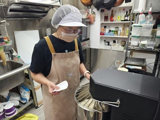 Food production worker shaping dough in a professional kitchen environment