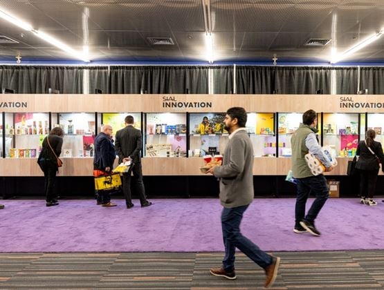 Visitors walking past the innovation area of a trade show showcasing food products.