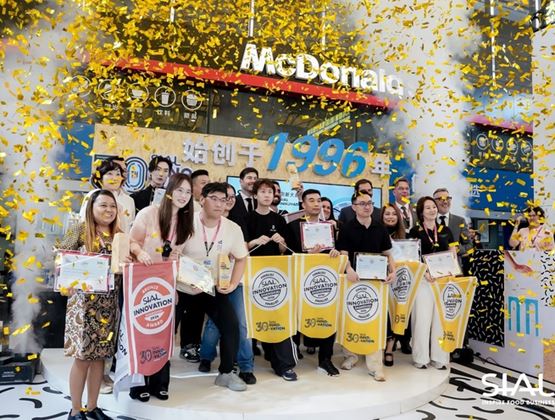 Winners of the SIAL Innovation Awards posing with certificates and trophies under a shower of gold confetti at the SIAL trade show in China.