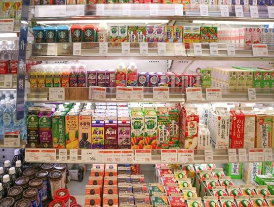 Shelves filled with colourful drinks and packaged food products in a Japanese convenience store.