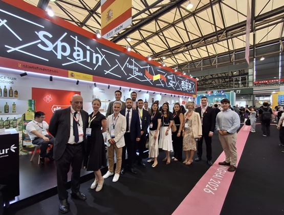 Group of exhibitors and representatives posing in front of the Spain pavilion at an international trade show.