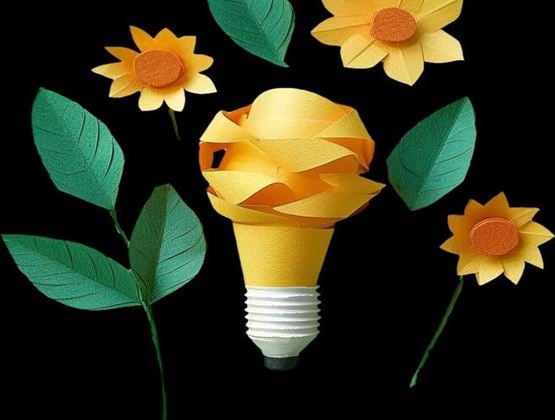 Yellow light bulb made from strips of paper, surrounded by green leaves and yellow flowers against a black background.