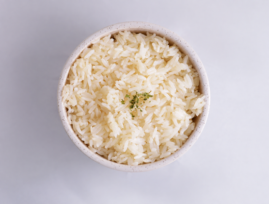 Bowl of cooked white rice viewed from above on a light background.