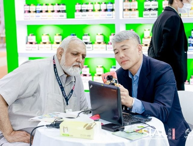 Two men discussing and analyzing a product during a B2B meeting at SIAL Shanghai.
