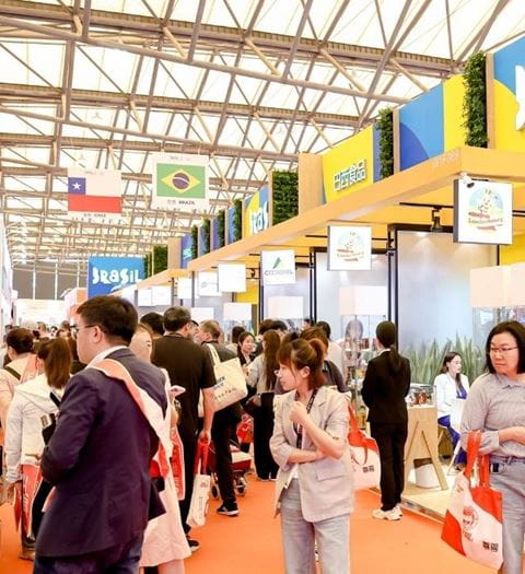 A bustling aisle at SIAL Shanghai, with numerous visitors exploring international stands, including those from Brazil and Chile.