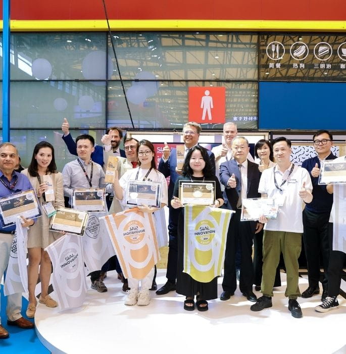 A group of SIAL Innovation Awards winners posing with their certificates and flags, celebrating their success on stage at SIAL Shanghai.