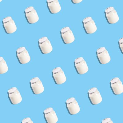 Yogurt jars arranged in a repeating pattern on a blue background, top view.