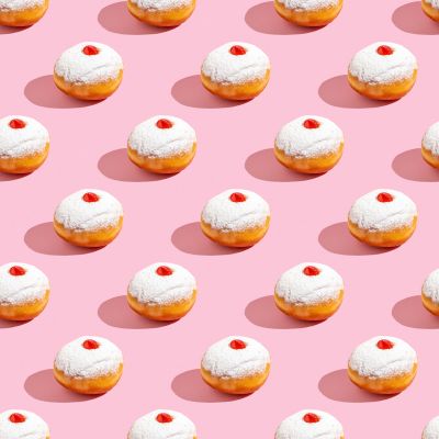 Powdered donuts with jam filling in a repeating pattern on a pink background.