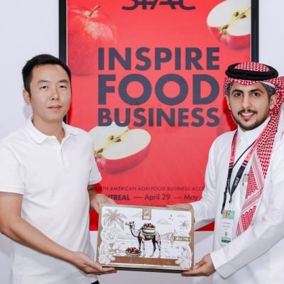 Two exhibitors posing in front of an Inspire Food Business sign at an international food trade show.