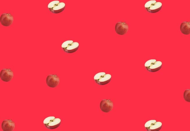 Repeating pattern of whole and sliced apples on a bright red background illustrating a vibrant fruit theme