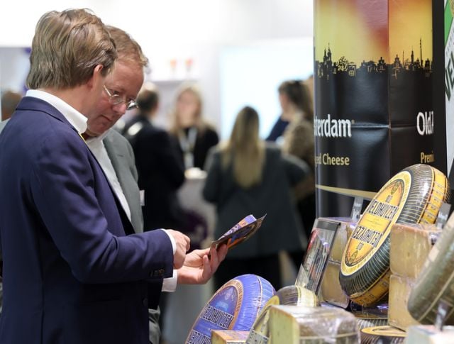 Buyers reviewing a product sheet at a cheese booth during an international food trade show