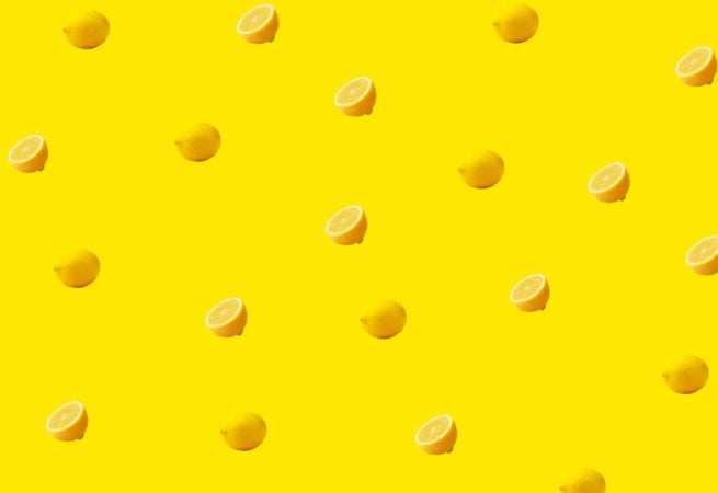 Pattern of whole and sliced lemons on a yellow background illustrating fresh and natural food