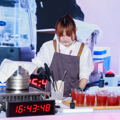 Contestant preparing specialty beverages during a live food innovation competition at SIAL Shanghai.