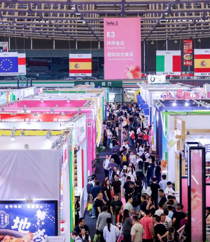 Visitors walking through crowded exhibition aisles at an international food and beverage trade show in Shanghai, China.