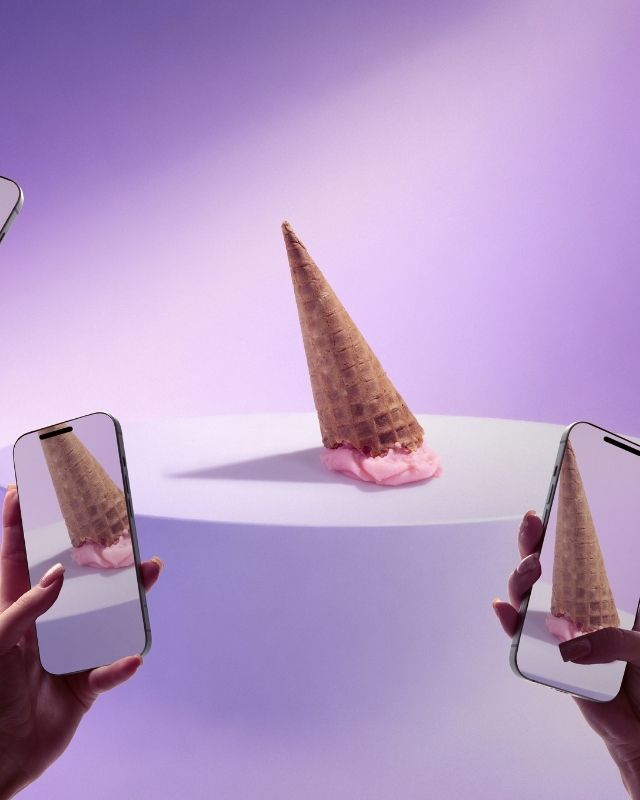 Smartphones photographing an upside-down ice cream cone on a minimalist set, illustrating digital content creation.