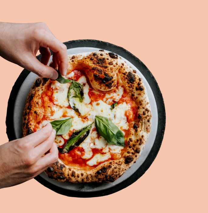 Margherita pizza with fresh basil on a pink background