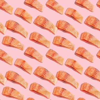 Salmon slices arranged in a repetitive pattern on a pink background.