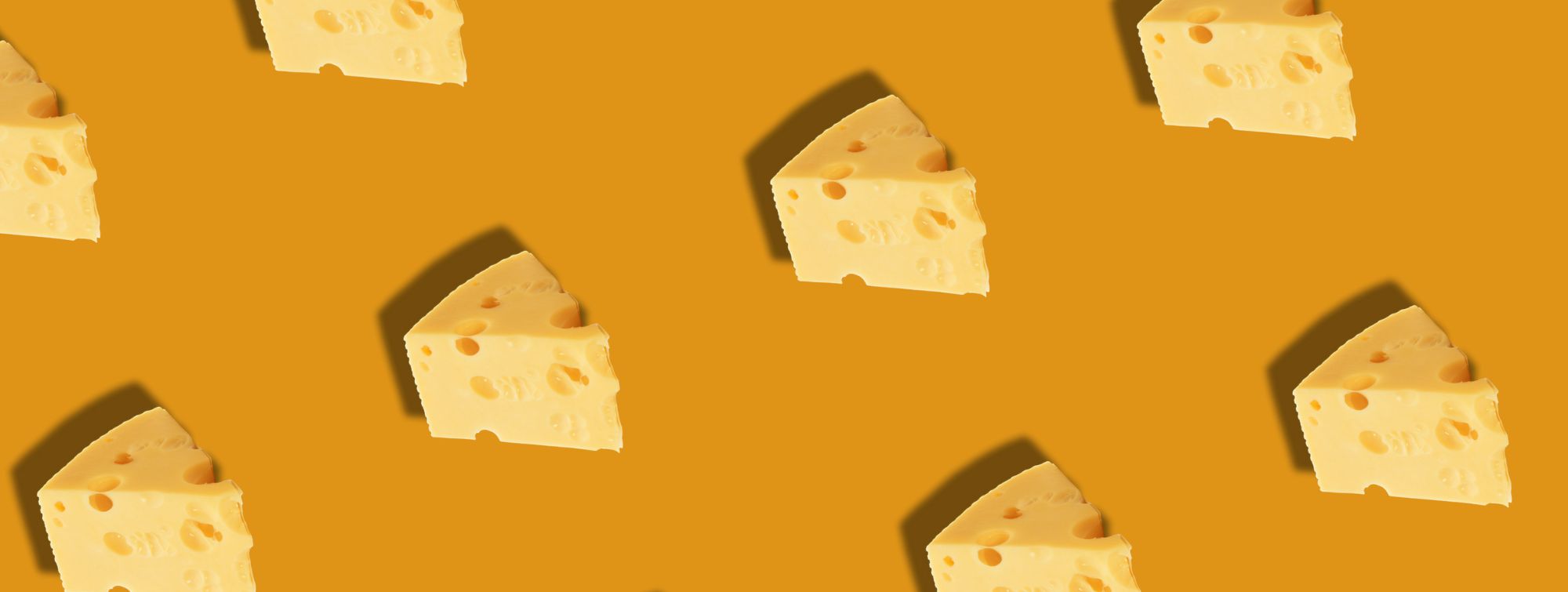 Banner with a pattern of emmental cheese pieces on an orange background, spaced with drop shadows.