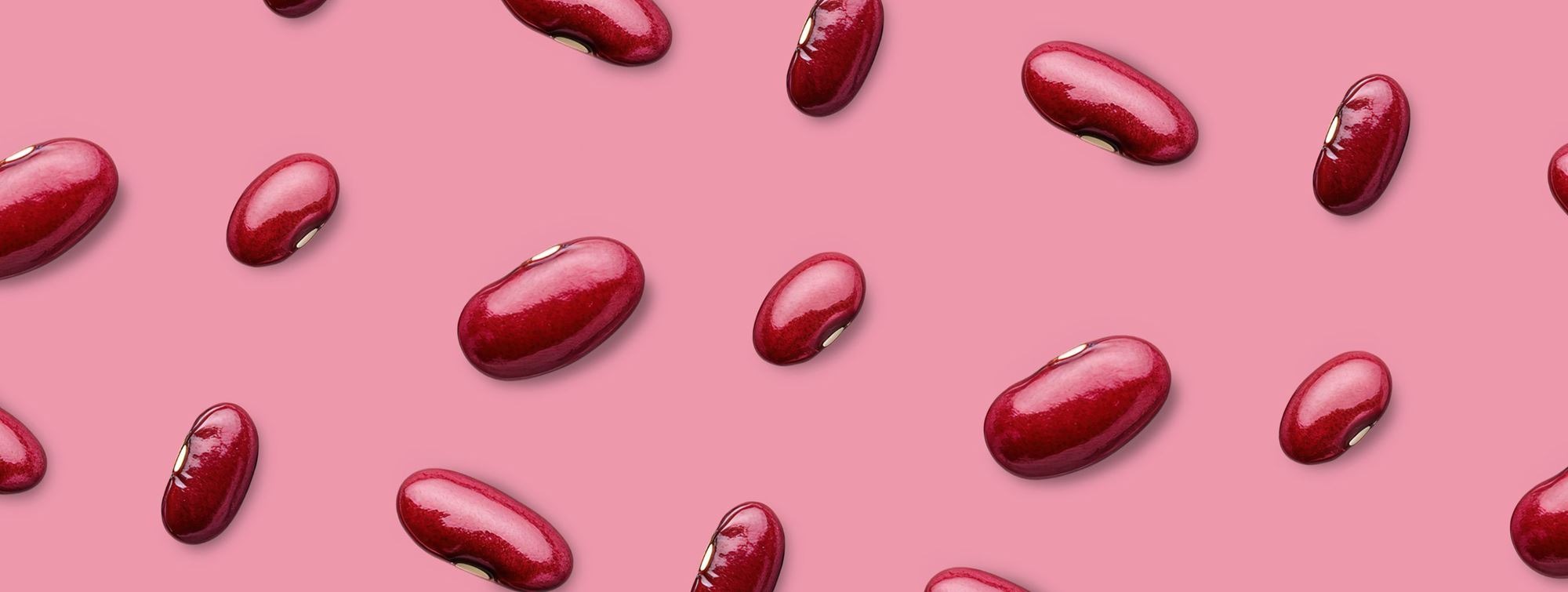 Red kidney beans scattered on pink background 