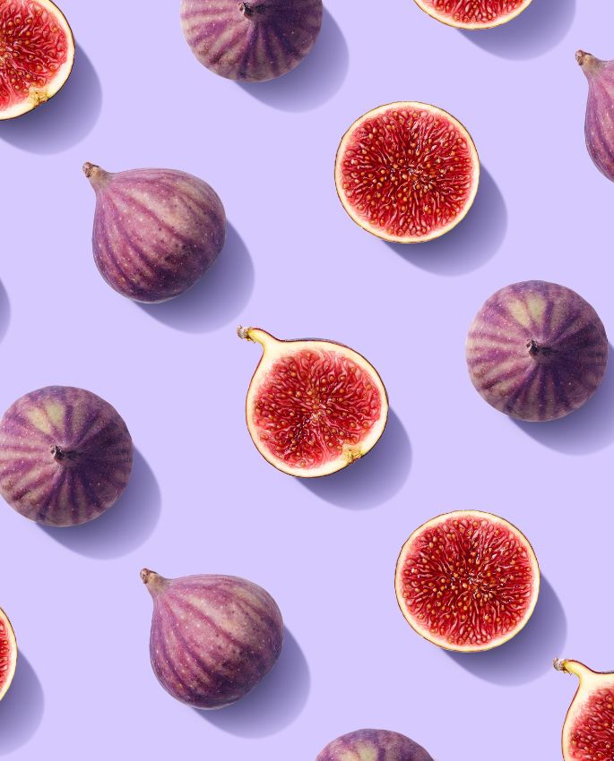 Pattern of whole and sliced figs on purple background, colorful contrast with detailed natural texture